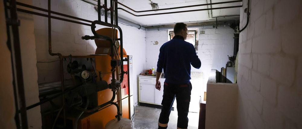 Ein Mitarbeiter eines Diesel- und Heizöl-Unternehmens prüft die Kunststofftanks in einem Heizungskeller bei der Heizöllieferung für ein Einfamilienhaus.