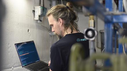 Ein Metr-Mitarbeiter kontrolliert digital die Anlage im Heizungskeller eines Hochhauses 