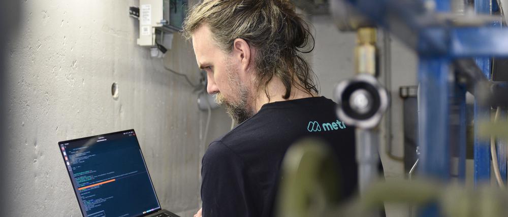 Ein Metr-Mitarbeiter kontrolliert digital die Anlage im Heizungskeller eines Hochhauses