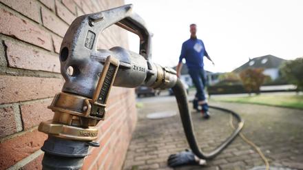 Ein Mitarbeiter eines Diesel- und Heizöl-Unternehmens geht zur Zapfpistole an einem Füllstutzen für die Heizöllieferung an einen Kunden in einem Einfamilienhaus. 
