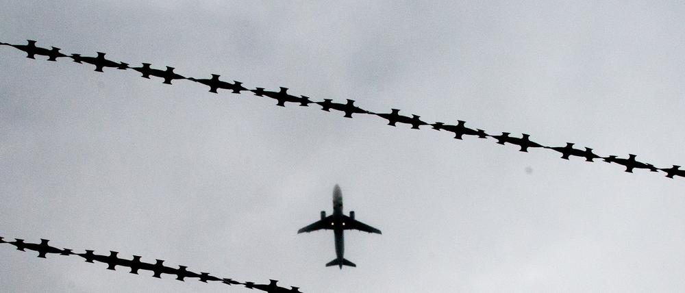 Ein Flugzeug ist hinter Stacheldraht zu sehen.
