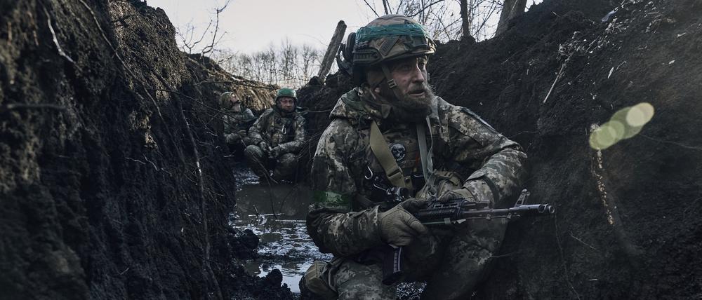 Ukrainische Soldaten hocken im Schlamm in einem Schützengraben an einer Frontlinie in der Nähe von Bachmut.