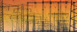 Die untergehende Sonne hat den Himmel hinter Hochspannungsleitungen verfärbt. 