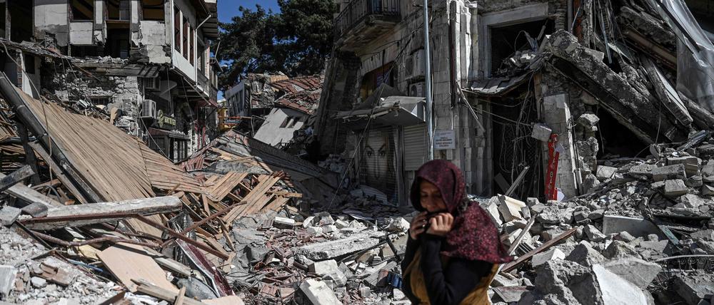 Eine Frau steht vor den Trümmern eines Hauses in Hatay. 