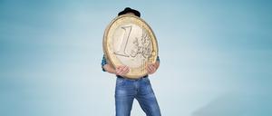 Ein Mann hält eine große, schwere Euro-Münze.