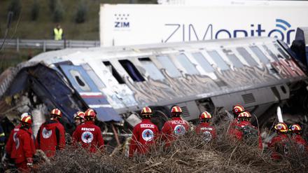 Rettungskräfte stehen in der Nähe von Zugtrümmern nach der Kollision.