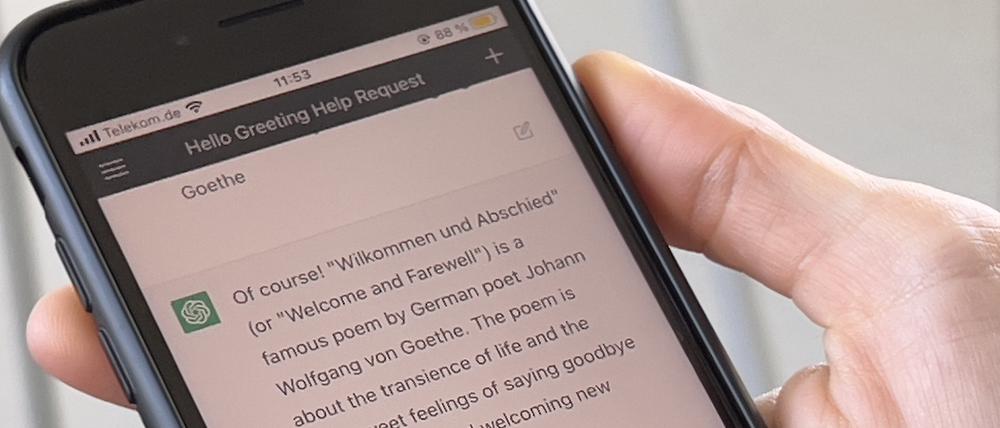 Eine Frau hält ein Smartphone mit der geöffneten Anwendung ChatGPT in der Hand.  