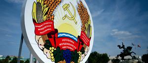 Eine Frau geht an einem riesigen Wappen von Transnistrien vorbei.