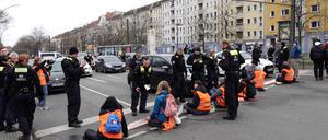 08.03.2023, Berlin: Bei einer Aktion der Letzten Generation blockieren Umweltaktivisten eine Kreuzung im Stadtteil Prenzlauer Berg. Ein Mann ging dabei die Aktivisten mehrfach an und riss an ihren Transparenten. Foto: Sven Käuler/dpa-Zentralbild/dpa +++ dpa-Bildfunk +++