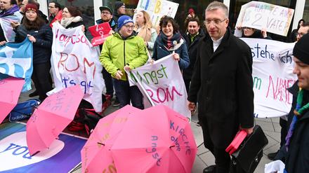 Michael Gerber, Bischof von Fulda, steht bei seiner Ankunft am Tagungsort der Synodalversammlung vor Demonstranten, die für die Gleichberechtigung von Frauen in der Kirche protestieren.