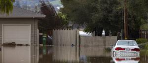 10.03.2023, USA, Watsonville: Ein Auto ist von Hochwasser umgeben.