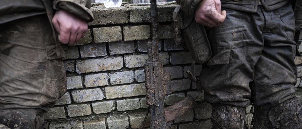Ein mit Schlamm verschmutztes Gewehr ist vor ukrainischen Soldaten zu sehen, die am 8. März von Tranchen von Bachmut zurückkommen.