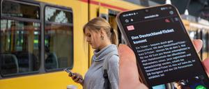 Nahaufnahme eines Smartphones vor einem Regionalzug