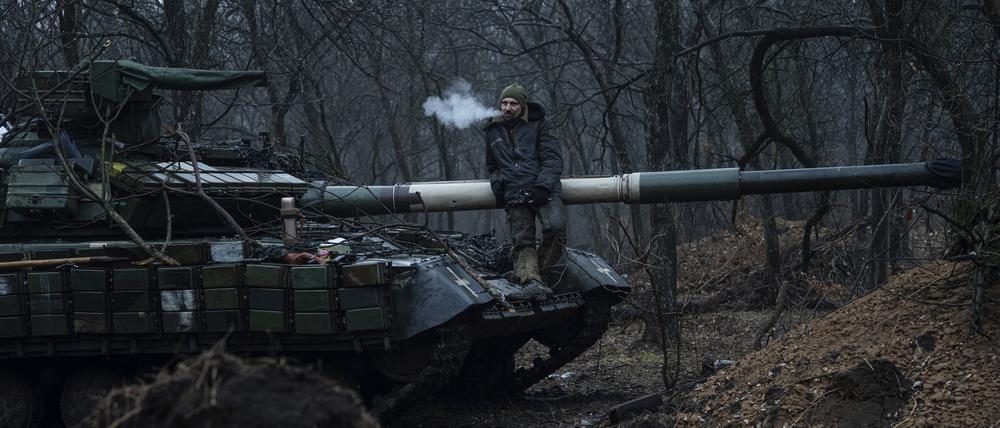 Ein ukrainischer Soldat raucht eine Zigarette oben auf einem Panzer.