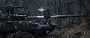 Ein ukrainischer Soldat raucht eine Zigarette oben auf einem Panzer. 
