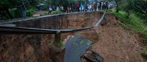 In Malawi gehen Menschen um ein durch den Zyklon verursachtes Loch herum. 