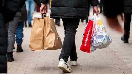 Ein Passant mit Einkaufstüten geht in der Innenstadt durch eine Einkaufsstraße.