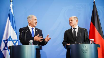 Benjamin Netanjahu erklärt Olaf Scholz etwas. 