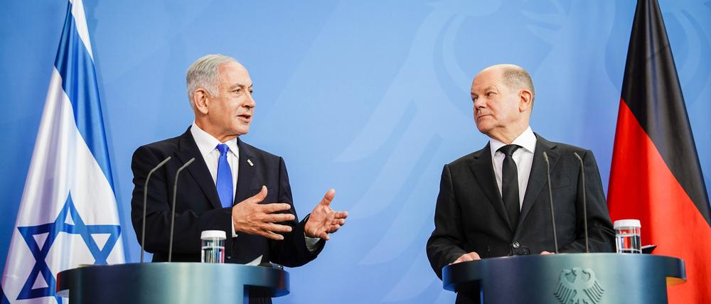 Benjamin Netanjahu erklärt Olaf Scholz etwas.