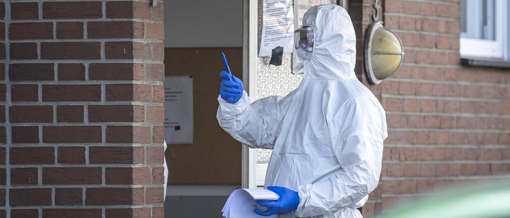 in Bundeswehr-Soldat im Schutzanzug und mit Mund-Nasenschutz betritt ein Wohnhaus, in dem Personen getestet werden.