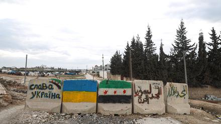 Die syrische und ukrainische Flagge auf Steinen im Norden von Aleppo, Syrien.