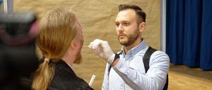 Ein Polizeibeamter demonstriert in einer gestellten Szene vor Beginn eines DNA Massentests die Abnahme einer DNA Probe.