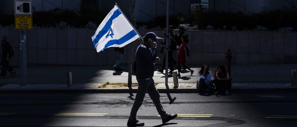 Ein israelischer Demonstrant hält eine Nationalflagge während eines regierungskritischen Protests (Symbolbild)