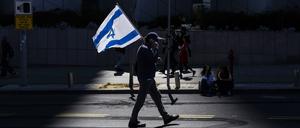 Ein israelischer Demonstrant hält eine Nationalflagge während eines regierungskritischen Protests (Symbolbild)