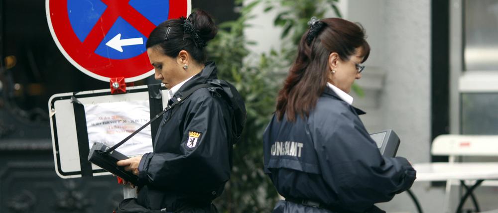 Zwei Politessen schreiben in Berlin die Kennzeichen von Autos auf, die im absoluten Halteverbot stehen.