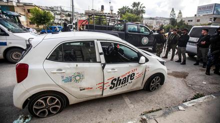 Palästinensische Sicherheitskräfte inspizieren ein von Israelis zerstörtes Auto, das von palästinensischen Jugendlichen mit Steinen beworfen wurde.