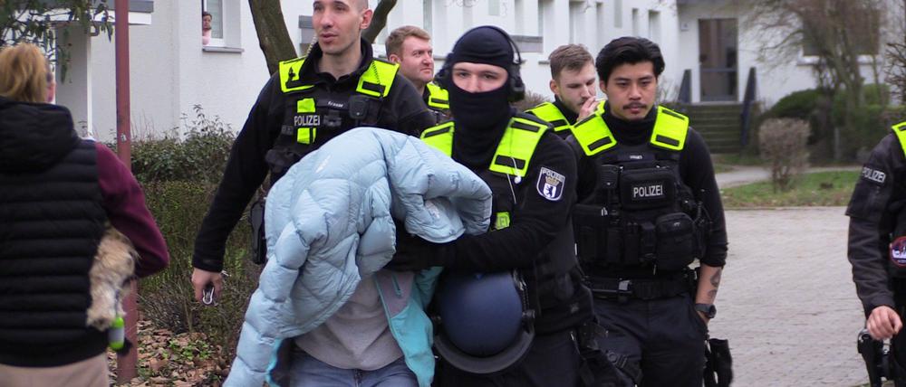 20.03.2023, Berlin: Polizisten führen einen Person ab. Eine randalierende Frau hat in Berlin-Hellersdo