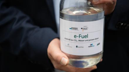 Ein Besucher hält eine Flasche mit E-Fuel aus einer Forschungsanlage des Karlsruher Instituts für Technologie (KIT) in den Händen.