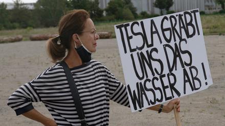 Eine Teilnehmerin an einer Demonstration gegen die Ansiedlung von Tesla in der brandenburgischen Gemeinde Grünheide mit einem Plakat mit der Aufschrift „Tesla gräbt uns das Wasser ab!“.