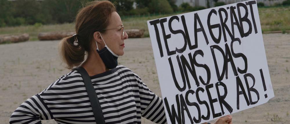 Eine Teilnehmerin an einer Demonstration gegen die Ansiedlung von Tesla in der brandenburgischen Gemeinde Grünheide mit einem Plakat mit der Aufschrift „Tesla gräbt uns das Wasser ab!“.
