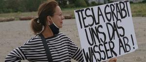 Eine Teilnehmerin an einer Demonstration gegen die Ansiedlung von Tesla in der brandenburgischen Gemeinde Grünheide mit einem Plakat mit der Aufschrift „Tesla gräbt uns das Wasser ab!“.
