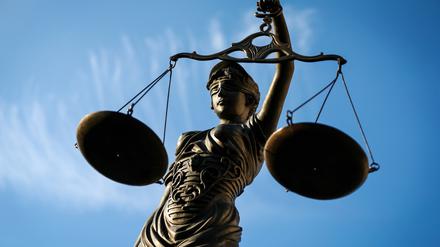Eine Statue der Justitia hält eine Waage in der Hand.