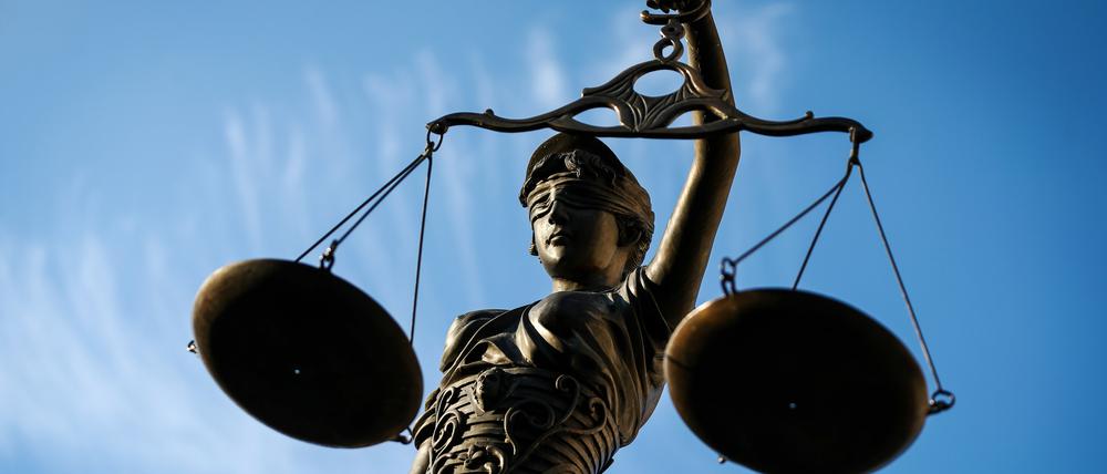 Eine Statue der Justitia hält eine Waage in der Hand.