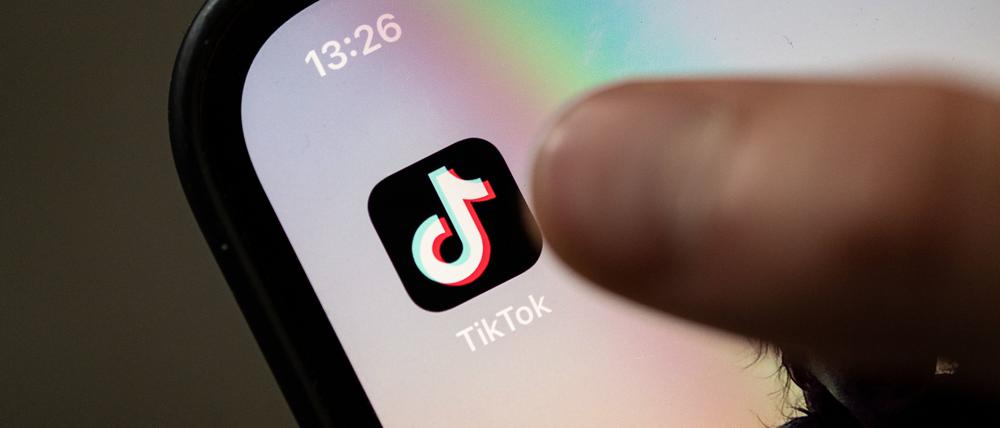 Ein Teenager tippt auf das Icon TikTok-App auf einem Smartphone. (Symbolbild).