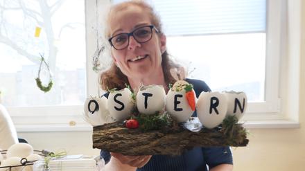 Katrin Behrens zeigt zwei handbemalte Ostereier mit dem Schriftzug „Ostern“ bei den Ostereiermarkttagen in der Bibliothek am Puschkinplatz in Gera.