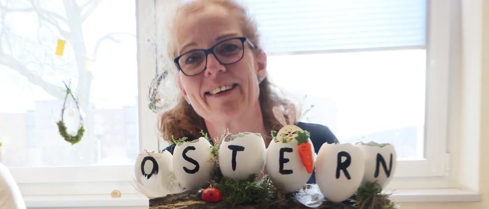Katrin Behrens zeigt zwei handbemalte Ostereier mit dem Schriftzug „Ostern“ bei den Ostereiermarkttagen in der Bibliothek am Puschkinplatz in Gera.