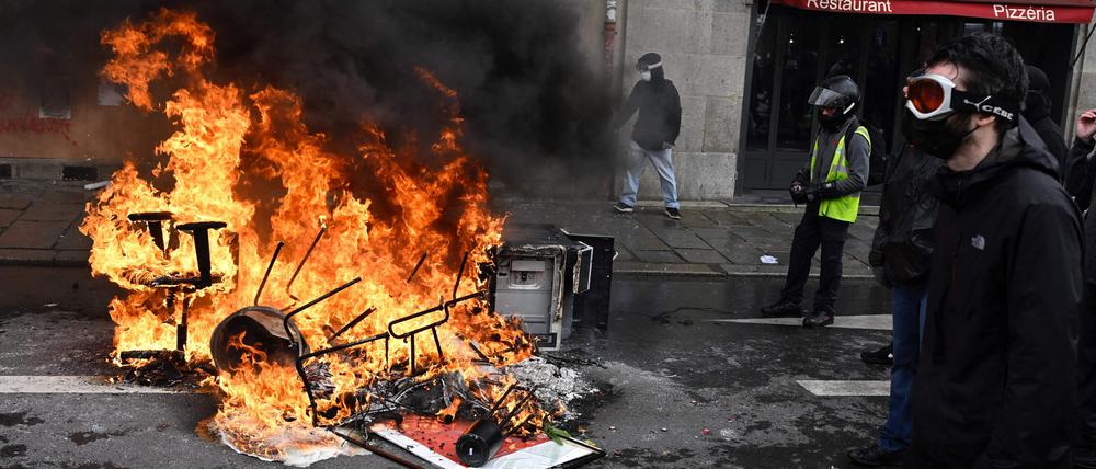 Ein Demonstrant geht während einer Kundgebung gegen das Gesetz zur Reform des Rentensystems in Rennes an brennenden Trümmern vorbei.