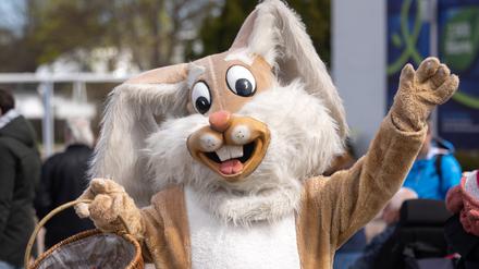 Ein Mensch in einem Osterhasenkostüm verteilt im Egapark Süßigkeiten.