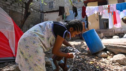 A woman washes a child at a makeshift refugee camp set up by people escaping gang activity in the Delmas 19 commune in Port-au-Prince, Haiti, on March 23, 2023, as gangs take over areas of Haiti. (Photo by Richard PIERRIN / AFP)