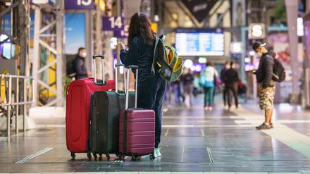 Eine Frau steht am frühen Morgen mit ihren Koffern im Frankfurter Hauptbahnhof. (Archivbild)