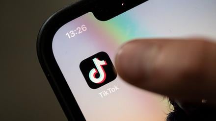 Ein Teenager tippt auf das Icon der Tiktok-App auf einem Smartphone.