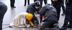 Polizisten lösen den Asphalt um die Hand einer festgeklebten Aktivistin in Hamburg.