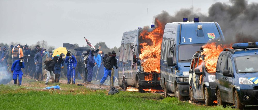 Demonstrierende stehen neben Polizeiwagen in Sainte-Soline. 