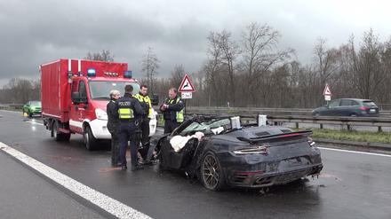 Polizisten stehen an dem Wrack eines Porsches auf der Autobahn 3. Vier Menschen sind bei kurz aufeinander folgenden Unfällen auf der A3 bei Emmerich am Niederrhein ums Leben gekommen - darunter auch ein Ersthelfer. Rettungshubschrauber, Notärzte und Krankenwagen waren den Angaben zufolge im Einsatz.
