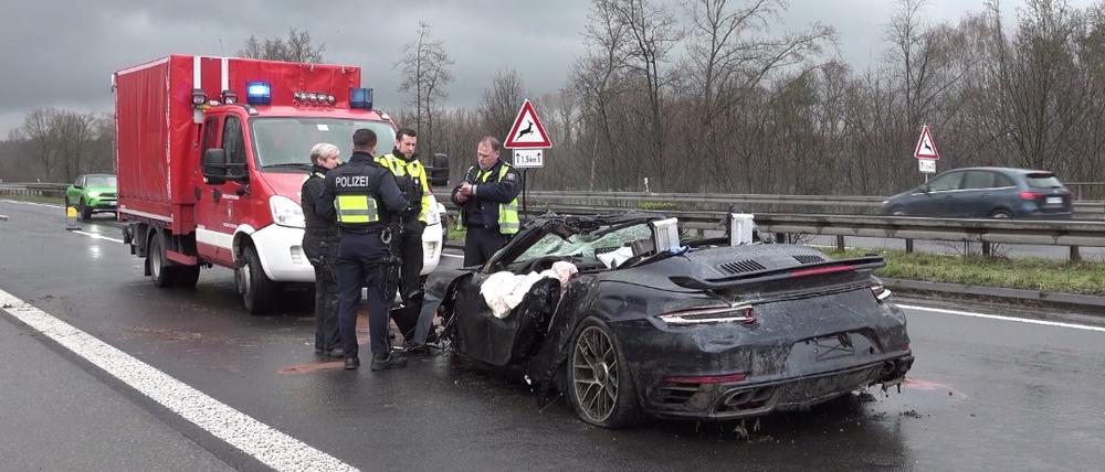 Polizisten stehen an dem Wrack eines Porsches auf der Autobahn 3. Vier Menschen sind bei kurz aufeinander folgenden Unfällen auf der A3 bei Emmerich am Niederrhein ums Leben gekommen - darunter auch ein Ersthelfer. Rettungshubschrauber, Notärzte und Krankenwagen waren den Angaben zufolge im Einsatz.