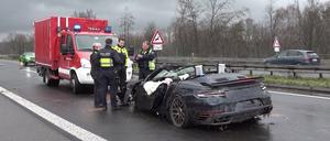 Polizisten stehen an dem Wrack eines Porsches auf der Autobahn 3. Vier Menschen sind bei kurz aufeinander folgenden Unfällen auf der A3 bei Emmerich am Niederrhein ums Leben gekommen - darunter auch ein Ersthelfer. Rettungshubschrauber, Notärzte und Krankenwagen waren den Angaben zufolge im Einsatz.